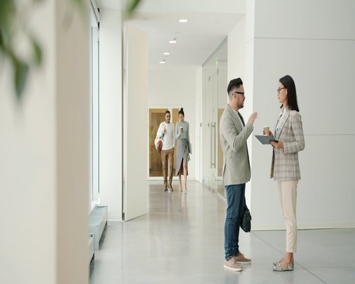 Colleagues walking and talking in an office hallway
