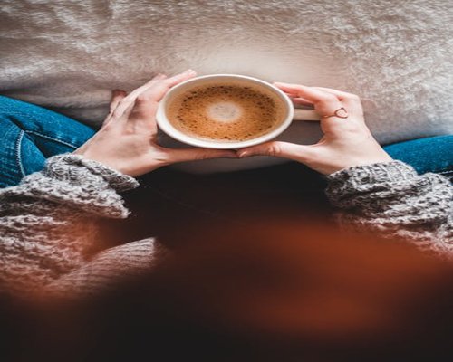 Person relaxing comfortably with a cup of warm drink