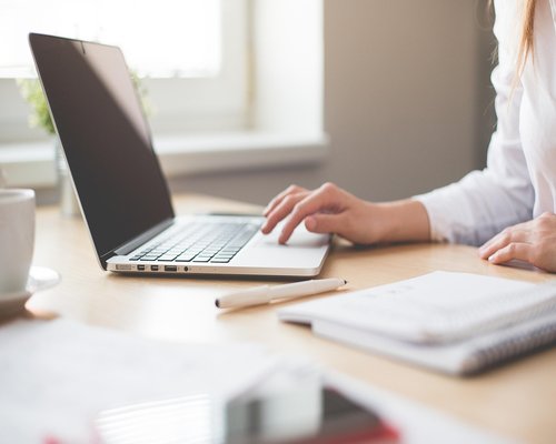 A person typing on a laptop at an office desk